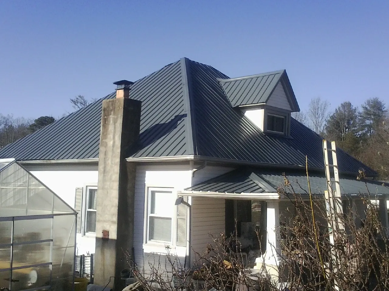 Dark blue standing seam metal roof on a white farmhouse with dormer — Slate & Tile Roof Repair by Roofing Brothers in Paden City