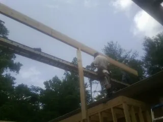 Carpenter setting a ridge beam over a new addition frame — Ice Dam Removal by Roofing Brothers in Paden City