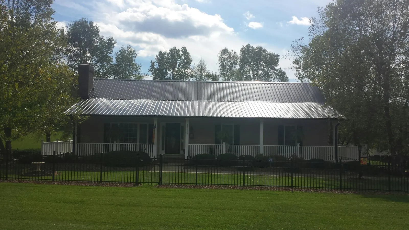 Gray metal roof on a brick ranch with a full width front porch — Gutter Guard Installation work by our crew in Paden City