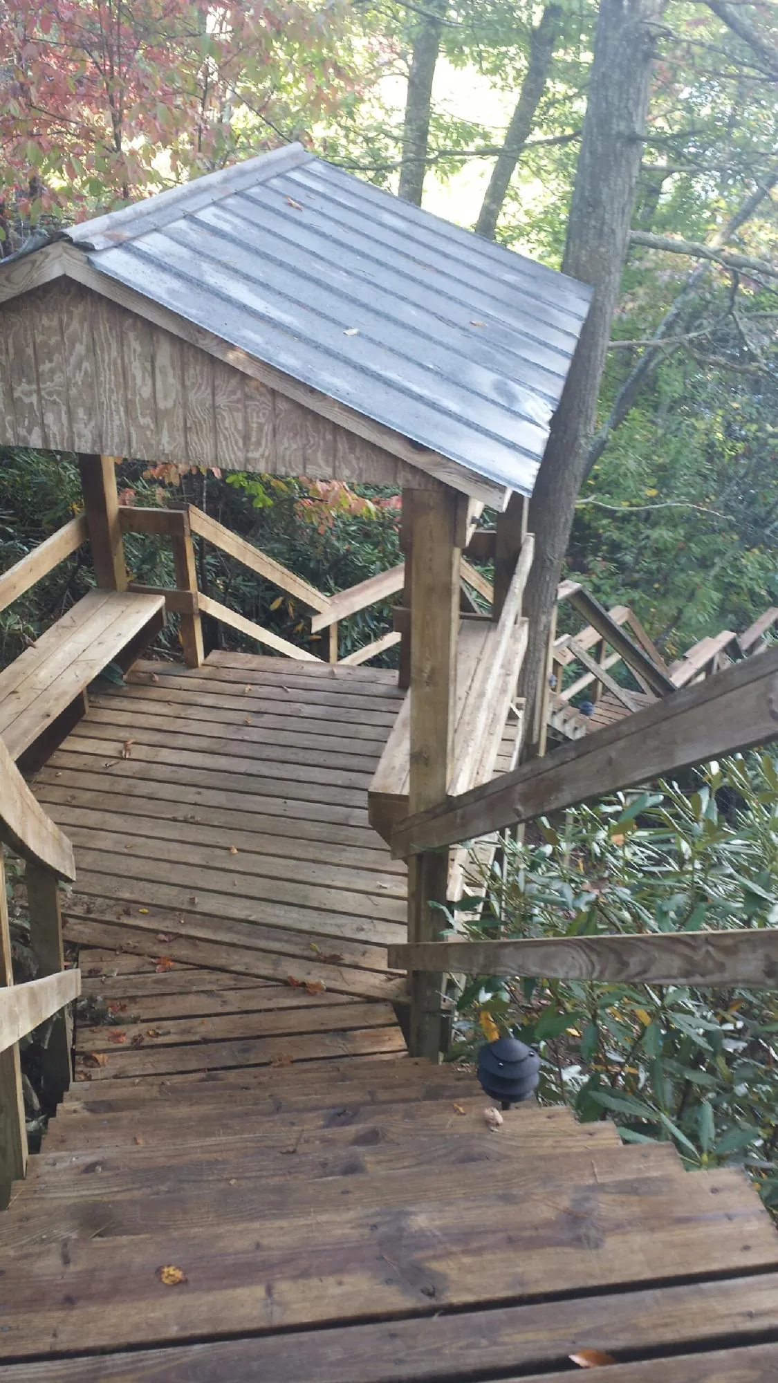 Metal roofed shelter over wooden steps on a wooded walkway — Skylight Repair & Installation work by our crew in Paden City