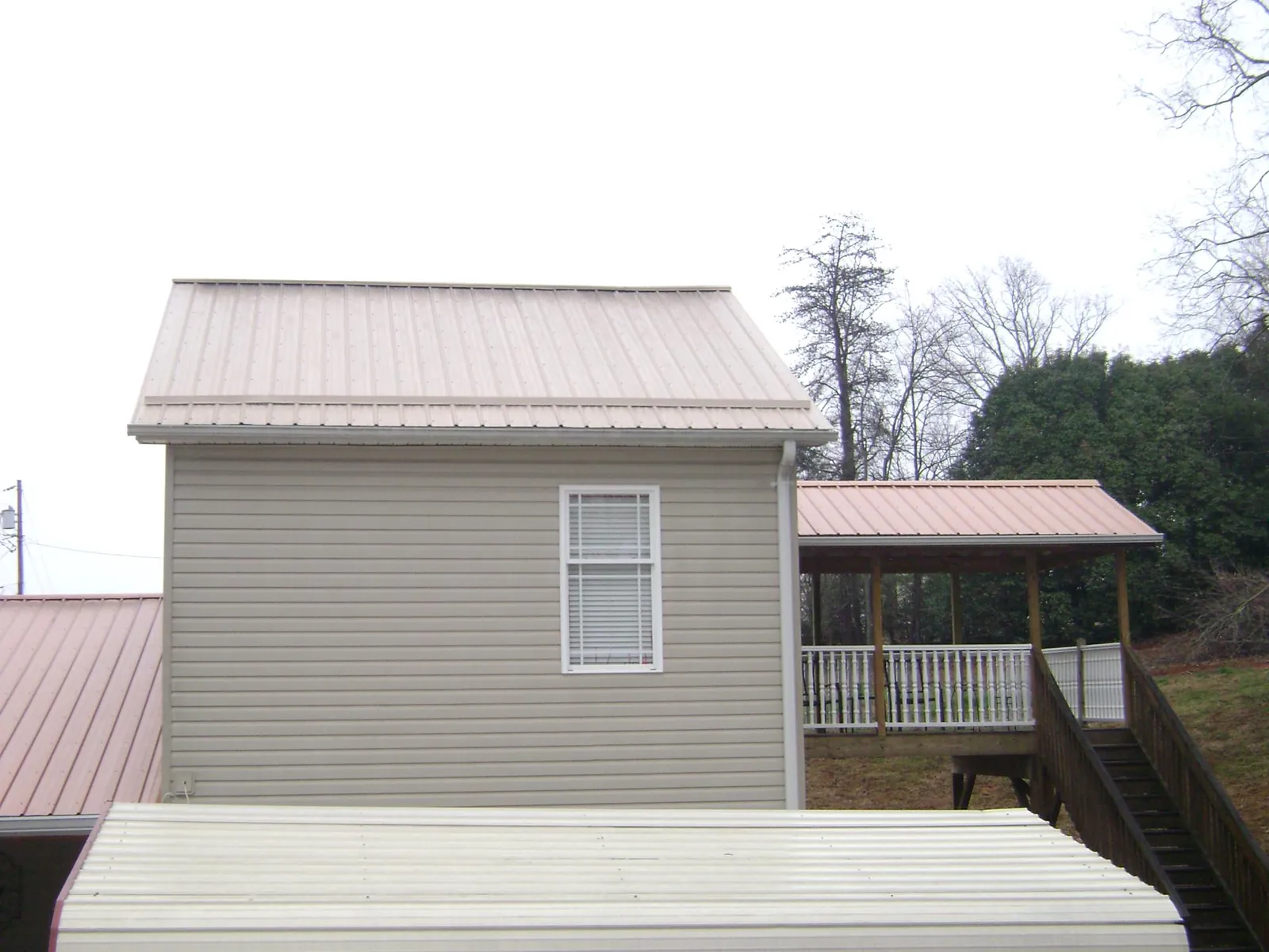 Tan metal roofs on a two story addition and attached porch, from a Roof Replacement job in Paden City