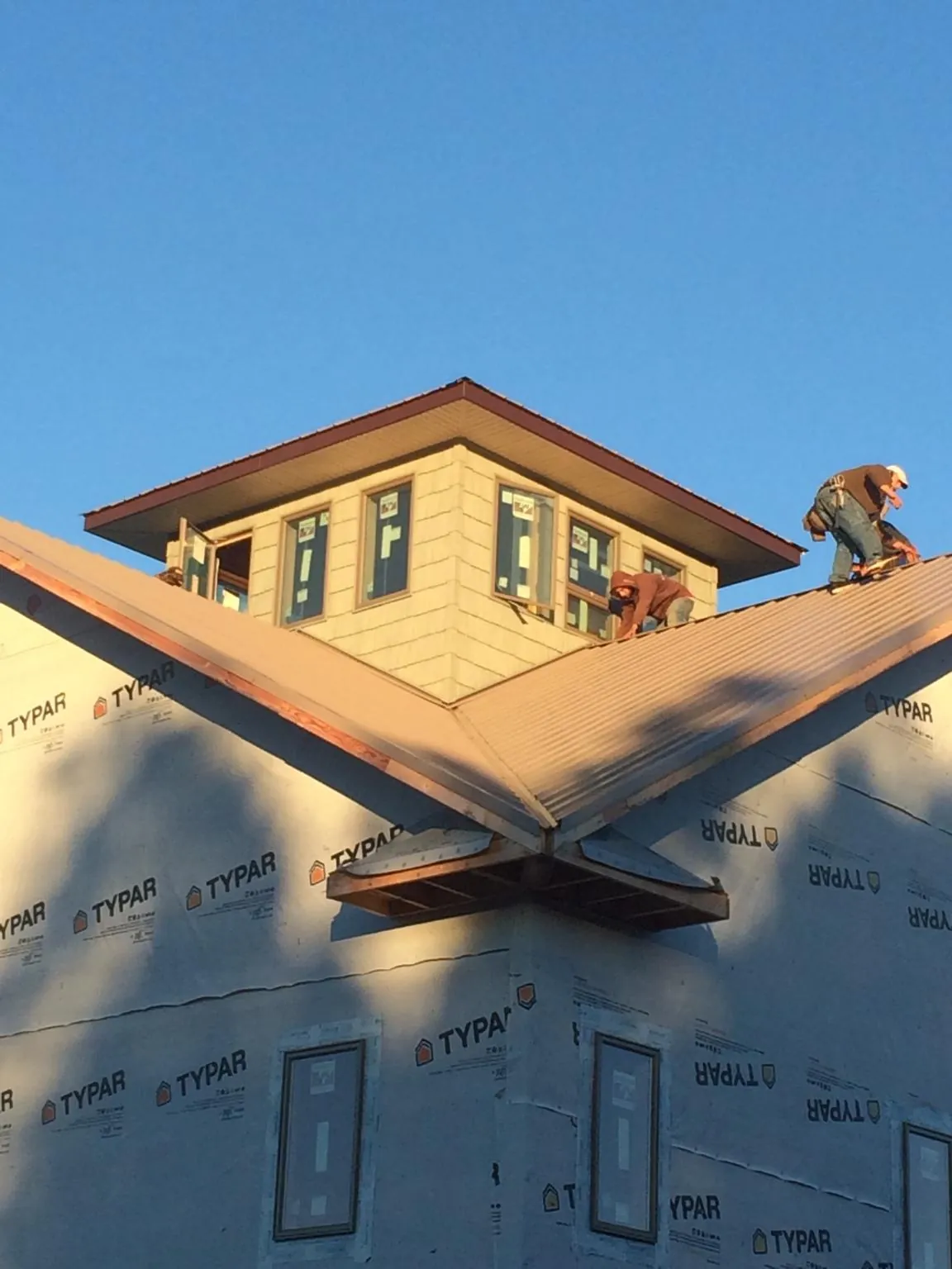 Roofers working around a rooftop cupola on a new metal roof at sunset — Roof Waterproofing in Paden City by Roofing Brothers